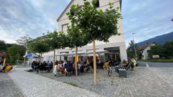 Belebte Terrasse des St. Martins Pub am Platz mit schattenspendenden Bäumen und Gästen an Tischen