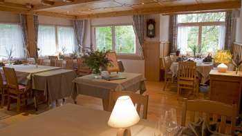 Gemütlicher Speiseraum mit gedeckten Tischen und gedimmtem Licht