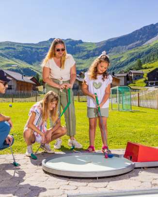 Familie spielt gemeinsam Minigolf im sonnigen Bergdorf Malbun in Liechtenstein