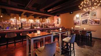 Elegantes Restaurant-Interieur mit dunklen Holzelementen, Barbereich und bequemen Stühlen in einem gemütlichen Ambiente.