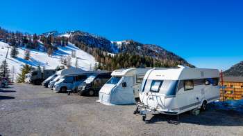 Mehrere Wohnmobile stehen auf dem sonnigen Stellplatz in Malbun mit Bergpanorama im Hintergrund