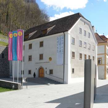 Blick auf das Liechtensteinische Landesmuseum in Vaduz mit historischen Gebäuden und bunten Fahnen