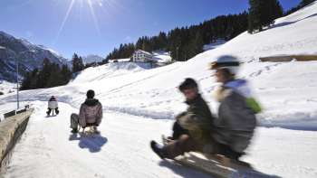 Lehrer Personen rodeln die Rodelstrecke an einem schönen sonnigen Tag in der Winterlandschaft