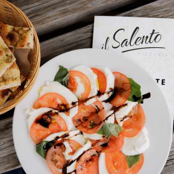 Frische Pizza mit Tomatensauce und Rucola, serviert auf rustikalem Holztisch