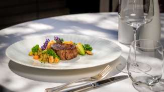 Exquisit angerichteter Fleischgang mit Gemüse und Blüten im Park Hotel Sonnenhof auf der Terrasse in Vaduz, Liechtenstein