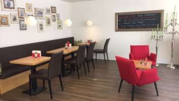  Gemütliches Café mit modernen Sitzmöbeln, dekorativer Bilderwand und warmem Holzboden