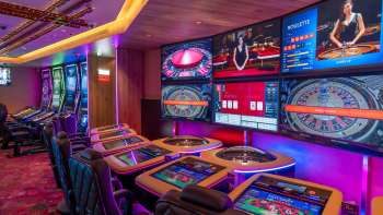 Moderne Spieltische mit digitalen Bildschirmen und mehreren Roulette- und Kartenspieloptionen im stimmungsvoll beleuchteten Casino Schaanwald.
