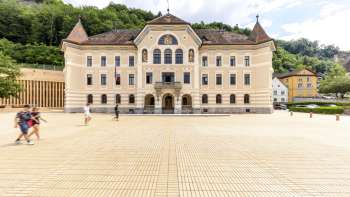 Regierungsgebäude Vaduz mit heller Fassade und Platz davor.