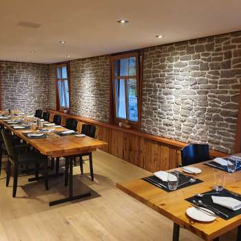 Stilvoller Gastraum mit langen Holztischen, Steinwänden und moderner Dekoration