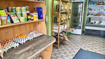  Innenansicht des Hofladens Aeulehof mit Regal voller regionaler Produkte, darunter Eier und Konserven.