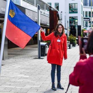 Stadtführerin präsentiert die Flagge Liechtensteins bei einer geführten Tour durch das Zentrum von Vaduz
