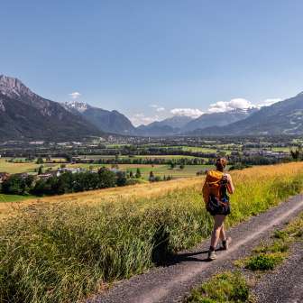 Frau wandert auf einem Feldweg mit Panorama-Aussicht über das Rheintal in Liechtenstein