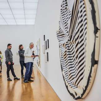 Besucher betrachten moderne Kunstwerke in einer Galerie des Kunstmuseums Liechtenstein mit heller Architektur und Holzfußboden