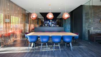 Modernes Restaurant mit stilvollem Interieur, blauen Designerstühlen und eleganter Bar im b_smart Hotel