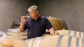 Winzer vom Weingut Hoop in Liechtenstein beim Verkosten des Weins direkt aus dem Holzfass im Weinkeller.