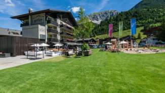 Familienfreundliches Hotel Gorfion in Malbun mit großer Spielwiese und Bergkulisse im Sommer