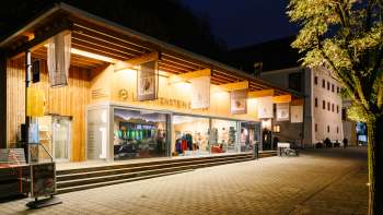 Modernes Besucherzentrum mit Glasfront in Vaduz bei Nacht, einladend beleuchtet.
