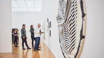 Besuchergruppe im Ausstellungsraum des Kunstmuseums, im Vordergrund ein großes, rundes Kunstwerk