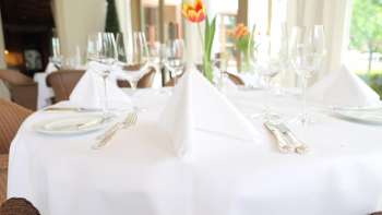 Festlich gedeckter Tisch mit weisser Tischdecke und frischer Tulpe