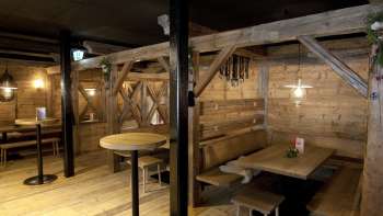 Gemütlicher Sitzbereich mit Holzbänken und Tischen im traditionellen Stil des Malbuner Lädeli Gemütlicher Sitzbereich mit Holzbänken und Tischen im traditionellen Stil des Malbuner Lädeli