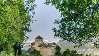 Zwei Personen geniessen vom Spazierweg aus die Aussicht auf das imposante Schloss Vaduz