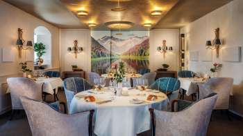 Eleganter Gastraum mit stilvoll gedeckten Tischen, edlem Ambiente und großem Landschaftsbild