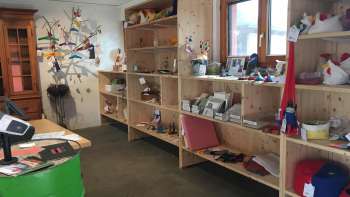 Innenraum des Birkahoflädile mit Holzregalen voller regionaler Produkte, dekorativ gestaltet mit bunten Elementen – Hofladen in Liechtenstein.