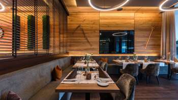 Moderner Restaurantbereich mit edler Holzausstattung, eleganten Tischen und bequemen Sesseln.