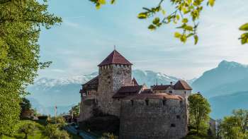 Malerischer Blick auf das Schloss Vaduz, eingebettet in grüne Hügel und Wälder.