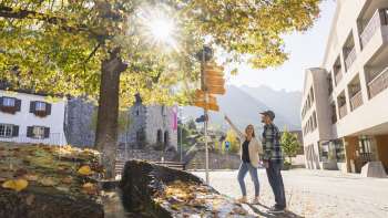 Herbstliche Szene mit Wanderweg-Wegweiser im Ortszentrum von Triesenberg