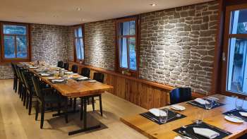 Stilvoller Gastraum mit langen Holztischen, Steinwänden und moderner Dekoration