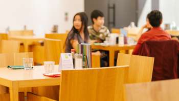 Gäste sitzen an Holztischen im Café im Kunstmuseum, plaudern entspannt und genießen die Atmosphäre. Gäste sitzen an Holztischen im Café im Kunstmuseum, plaudern entspannt und genießen die Atmosphäre.