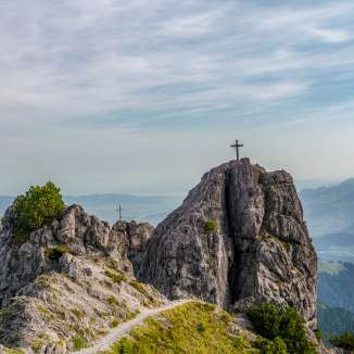 Zwei Gipfelkreuze auf den Felsen der Drei Schwestern mit Ausblick über das Rheintal entlang der Route 66 in Liechtenstein