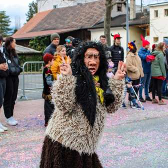 Verkleidete Schaaner Hexe beim Fasnachtsumzug in Schaan, Liechtenstein, vor Publikum und buntem Konfetti auf der Straße