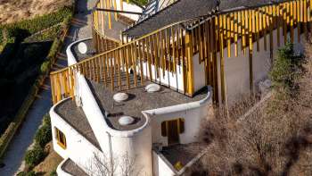 Luftaufnahme des kunstvoll geschwungenen Daches und der goldenen Fassadenelemente des Centrum für Kunst in Vaduz.