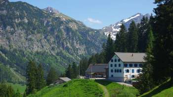 Das Berghaus Sücka in Triesenberg eingebettet in grüne Hänge mit Blick auf die umliegenden Alpen.