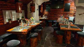 Blick auf ein rustikal eingerichtetes Restaurant mit Holzmöbeln, grün dekorierten Tischen und Kerzen