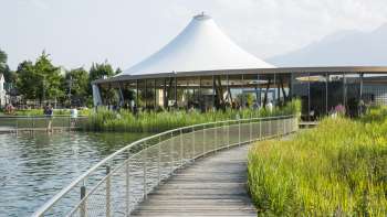 Moderner Pavillon am Wasser in der Freizeitanlage Grossabünt, umgeben von Natur und mit Blick auf die Alpen