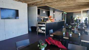 Moderner Gastraum mit dunklen Tischen, frischen Blumenarrangements und rustikalem Holzdach