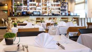  Geschmackvoll gedeckter Tisch im Restaurant Alpspitz mit Blick auf die Bar im Hintergrund.