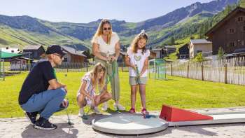 Familie spielt Minigolf auf der Alpen-Minigolf-Anlage in Malbun