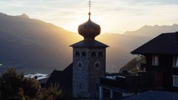 Zwiebelturm der Pfarrkirche St. Josef mit untergehender Sonne im Hintergrund
