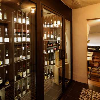 Moderner Weinschrank mit edlen Flaschen in der stilvollen WY Weinbar, Blick in den angrenzenden Verkostungsraum.