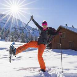 Fröhliche Schneeschuhwanderin geniesst den Winter in Malbun, Liechtenstein, unter strahlender Sonne.