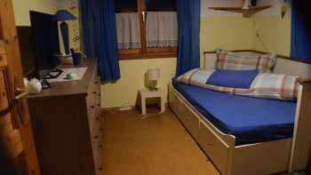 chlafzimmer im Studio in Eschen mit Bett, TV, Kommode und Fenster mit Vorhängen.