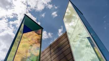Kunstinstallation „Zwei Licht-Prismen“ von Heinz Mack mit farbig schimmernden Glasflächen vor blauem Himmel.