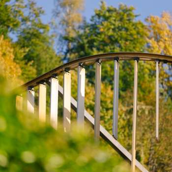 Nahaufnahme des gewölbten Metallbogens mit vertikalen Lamellen des Centrum für Kunst vor herbstlicher Waldkulisse in Vaduz.