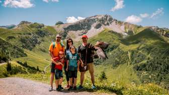 Familienshooting mit Adler in Malbun Familie posiert im Sommer mit einem Adler vor der beeindruckenden Bergkulisse von Malbun in Liechtenstein.