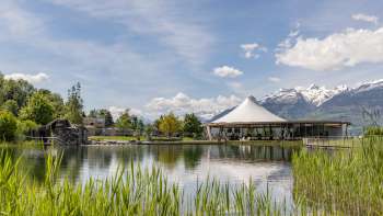 Moderner Pavillon am Wasser in der Freizeitanlage Grossabünt in Liechtenstein, umgeben von Natur und mit Blick auf die Alpen.