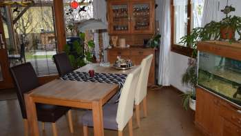 Freundlicher Essbereich im Studio in Eschen mit Holztisch, Aquarium und viel Tageslicht.